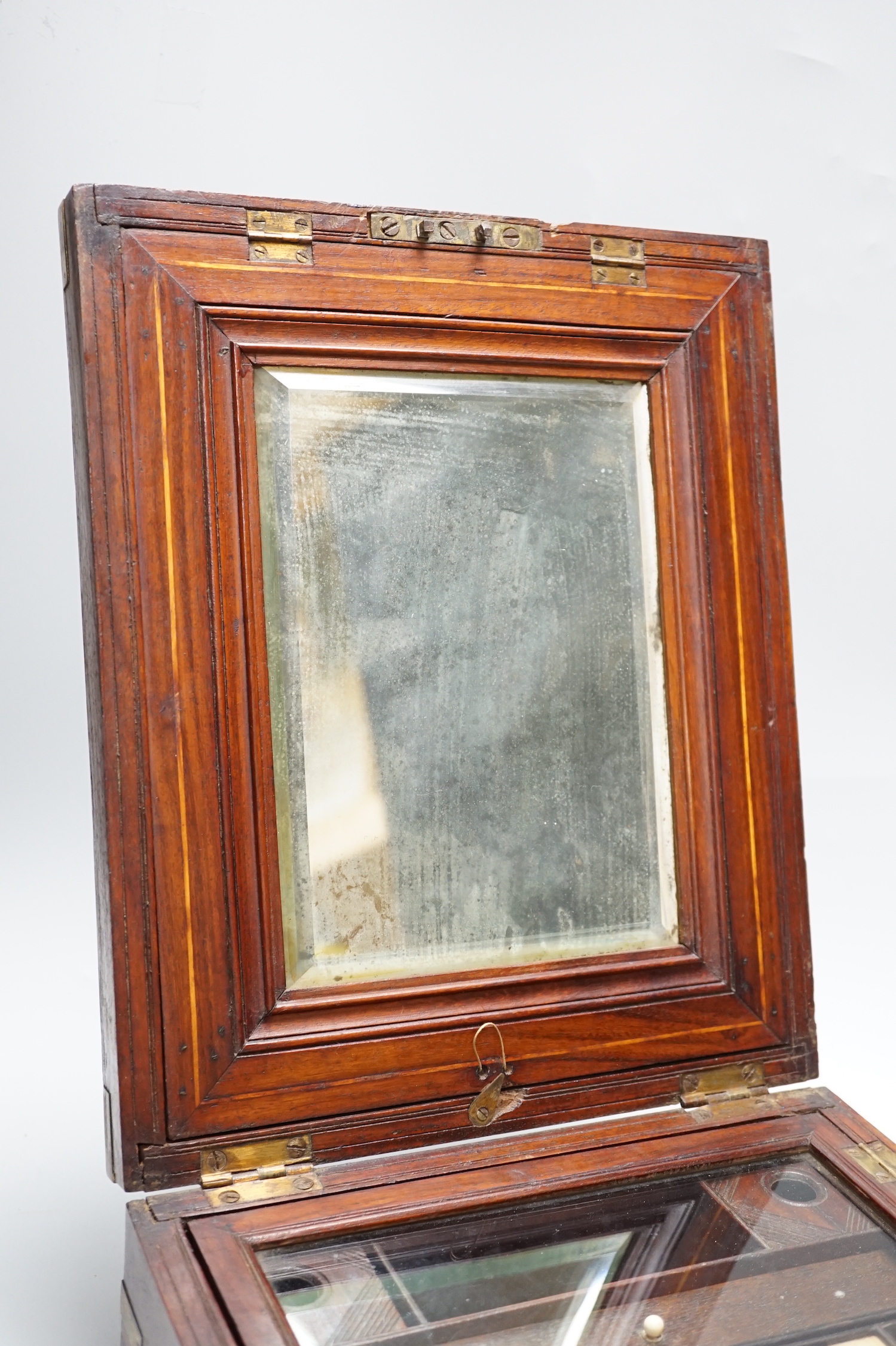 An Anglo-Indian wooden brass bound sewing box, with fitted interior and removable sections, hinged bevelled mirror, internal glass lid, etc. lock marked Birmingham, 26cm x 31cm x 14cm